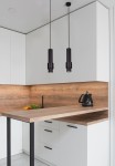 Lampa wisząca Roto 1xGU10 w kolorze czarnym, zawieszona na cienkich linkach, umieszczona nad drewnianym blatem w nowoczesnej kuchni. W tle białe szafki kuchenne i elementy drewniane, z widoczną czarną czajnikiem i świeżymi warzywami.