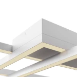 Lampa sufitowa LED Rida o mocy 78W w białej obudowie, z prostokątnym, minimalistycznym designem. Widoczny element montażowy oraz ciepłe, neutralne światło emitowane przez wbudowane diody LED. Ujęcie z góry, ukazujące szczegóły konstrukcji.