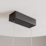 Lampa wisząca LED Skyline, czarna z elementami złotymi, z prostokątnym, matowym uchwytem montażowym. Wisi na cienkich, metalowych linkach. Źródło światła o mocy 26W i temperaturze barwowej 4000K. Widok z góry na lampę zamontowaną na suficie.