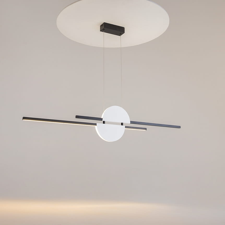 Lampa wisząca LED Skyline, czarna i biała, z okrągłym elementem centralnym oraz dwoma poziomymi, prostokątnymi paskami. Ujęcie z góry, zawieszona na cienkich linkach. Świetliste źródło 26W, temperatura barwowa 4000K. Tło jasne, minimalistyczne.