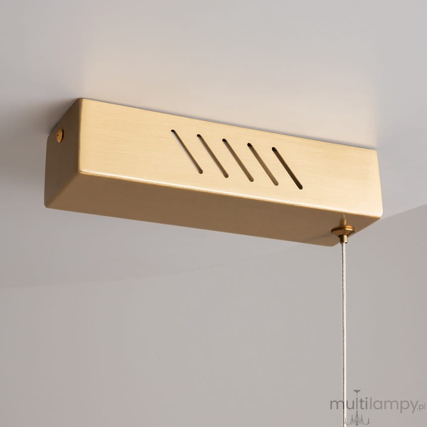 Lampa wisząca LED Petra w kolorze mosiądzu, o prostokątnej formie. Posiada wycięcia w górnej części i przewód z regulacją wysokości. Źródło światła o mocy 35W i temperaturze barwowej 3000K, montowana pod sufitem.