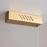 Lampa wisząca LED Petra w kolorze mosiądzu, o prostokątnej formie. Posiada wycięcia w górnej części i przewód z regulacją wysokości. Źródło światła o mocy 35W i temperaturze barwowej 3000K, montowana pod sufitem.