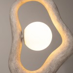 Lampa wisząca Opus w kolorze szarym, z okrągłą, mleczną żarówką G9. Oryginalny, organiczny kształt z teksturą przypominającą beton, z delikatnym podświetleniem. Ujęcie zbliżone na detal lampy, podkreślające fakturę i kształt.