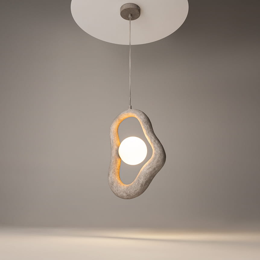Lampa wisząca Opus w kolorze szarym z jednym źródłem światła G9. Owalny, teksturowany klosz z wycięciem, w którym umieszczona jest okrągła żarówka, zawieszona na cienkim przewodzie. Tło jednolite, szare.