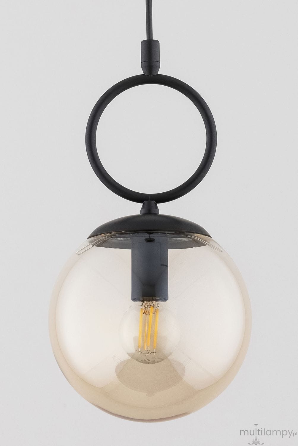 Lampa wisząca Sitro z czarnym metalowym elementem oraz bursztynową, szklaną kulą. Ujęcie frontalne, zawieszona na cienkim kablu. Wewnątrz widoczna żarówka E14. Prosta forma, idealna do nowoczesnych wnętrz.