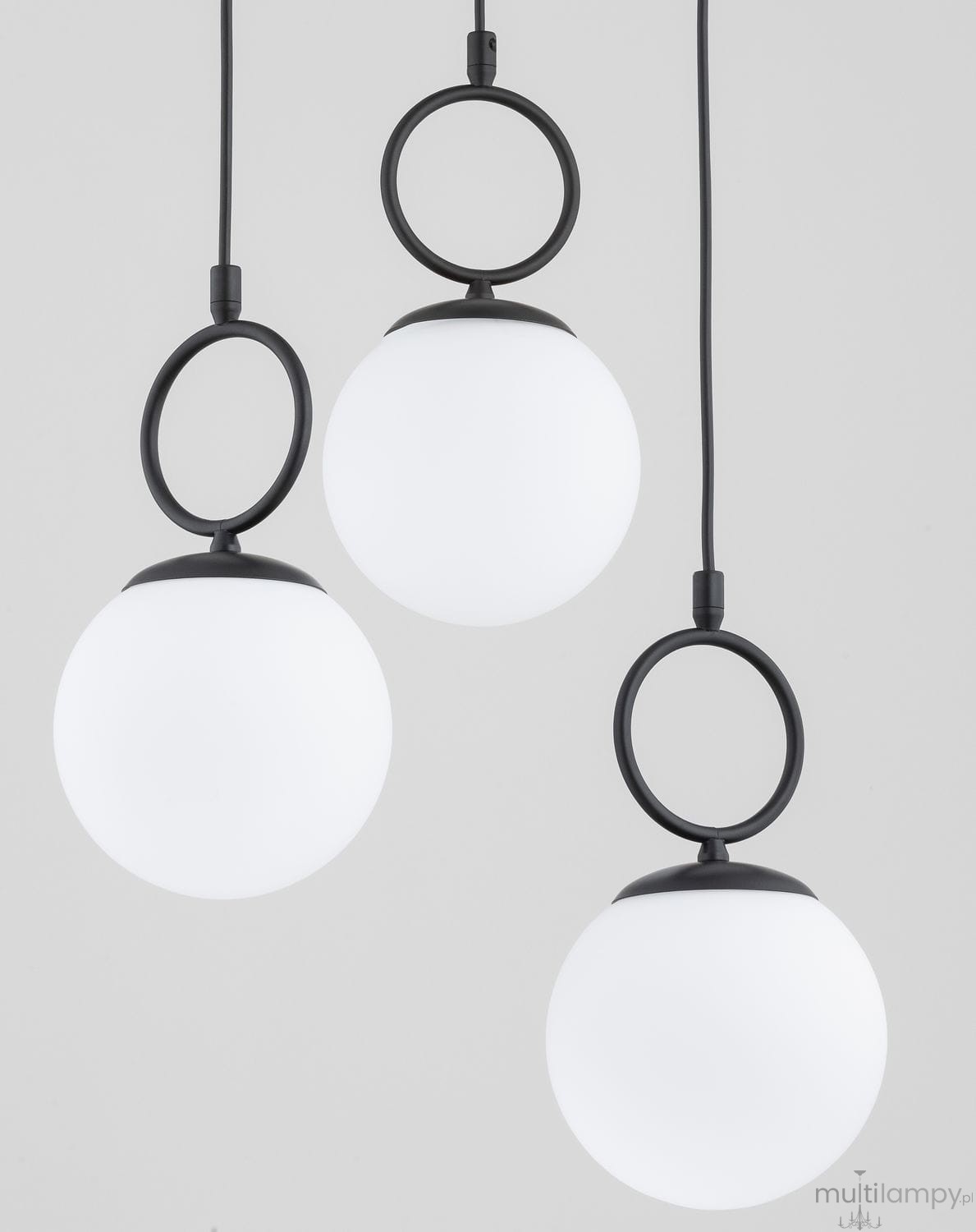 Lampa wisząca Sitro z trzema białymi, okrągłymi kloszami na czarnych mocowaniach. Klosze zawieszone są na cienkich przewodach, tworząc nowoczesny design. Całość na jasnym tle, podkreślającym elegancki styl lampy.