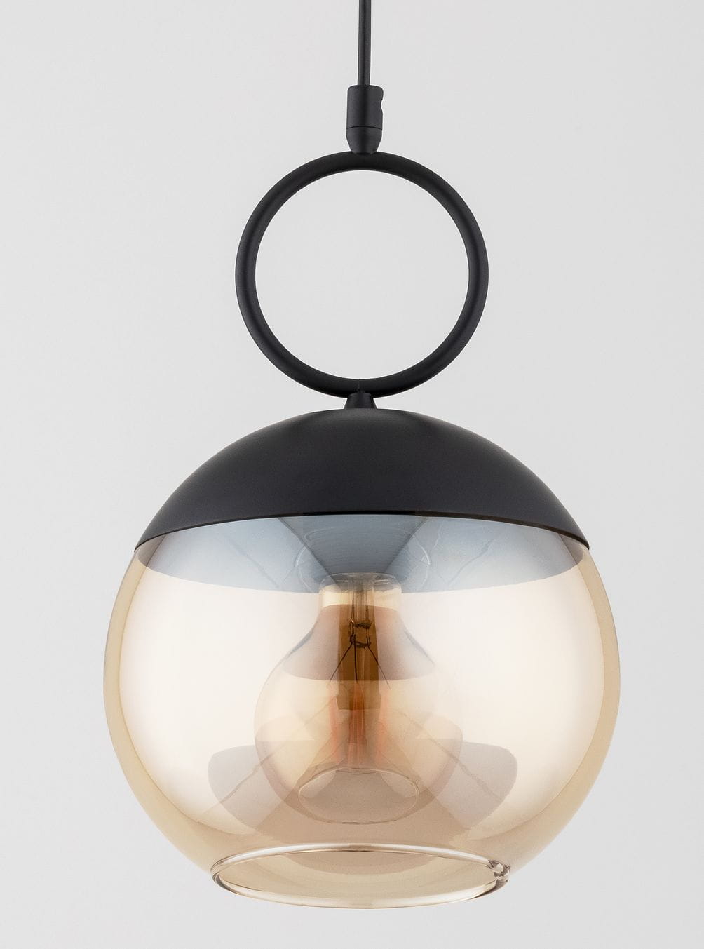 Lampa wisząca Sitro 20, z czarnym metalowym wykończeniem i bursztynowym kloszem w kształcie kuli. Posiada okrągły uchwyt, pojedyncze źródło światła E27 i nowoczesny design. Zawieszona w centralnej pozycji na jednolitym tle.