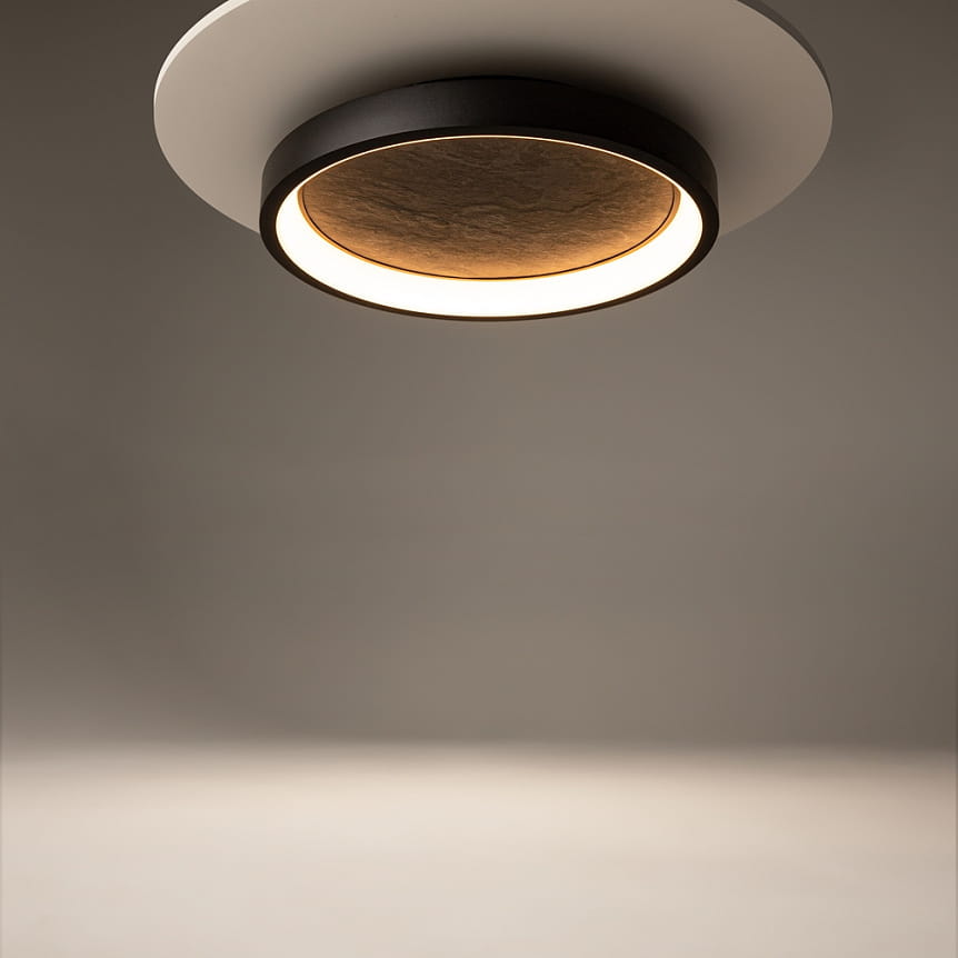 Lampa sufitowa LED Orign w kolorze czarnym o mocy 27W i temperaturze barwowej 3000K. Okrągła, z matowym wykończeniem, z centralnym elementem w kolorze brązowym. Zawieszona w pozycji poziomej, na prostym tle.