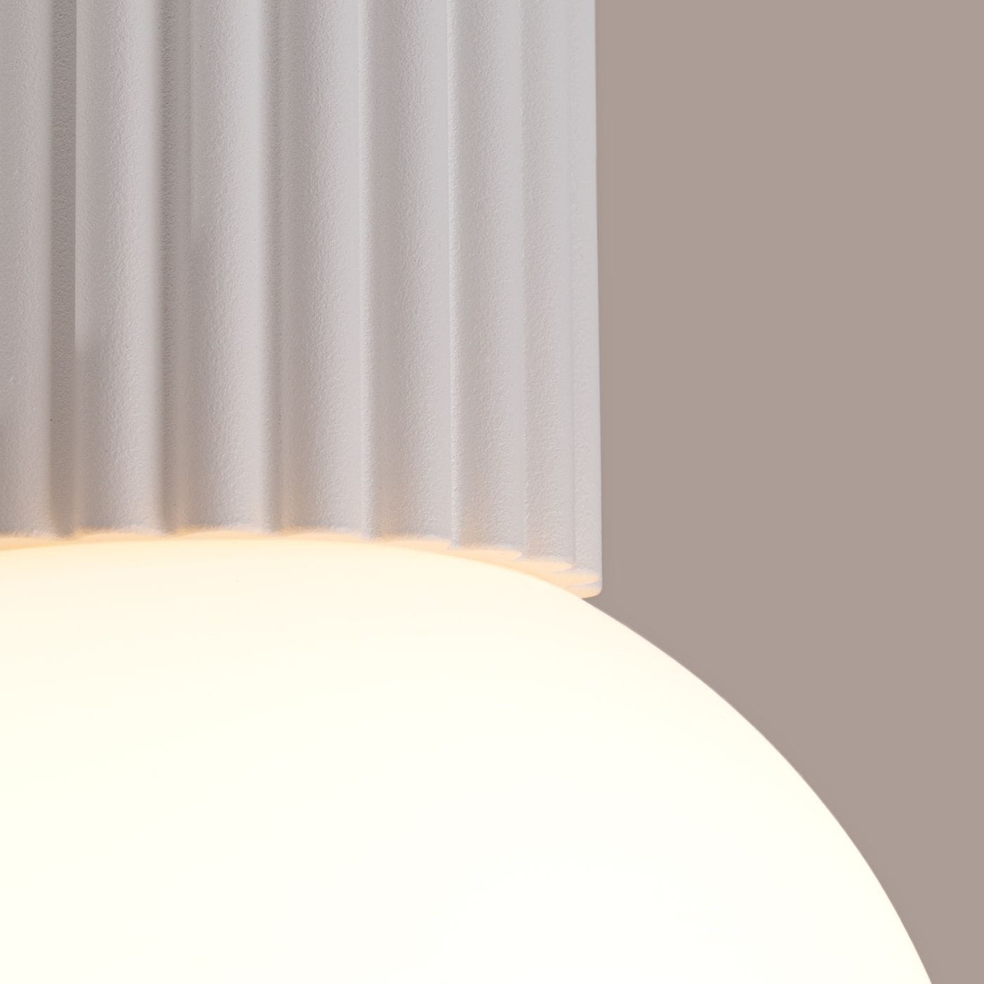 Biała lampa sufitowa Halo z kloszem w kształcie kuli i żebrowanym elementem mocującym. Ujęcie z bliska, ukazujące teksturę i detale. Przeznaczona do montażu sufitowego, z oprawą na żarówkę G9, stopień ochrony IP44.