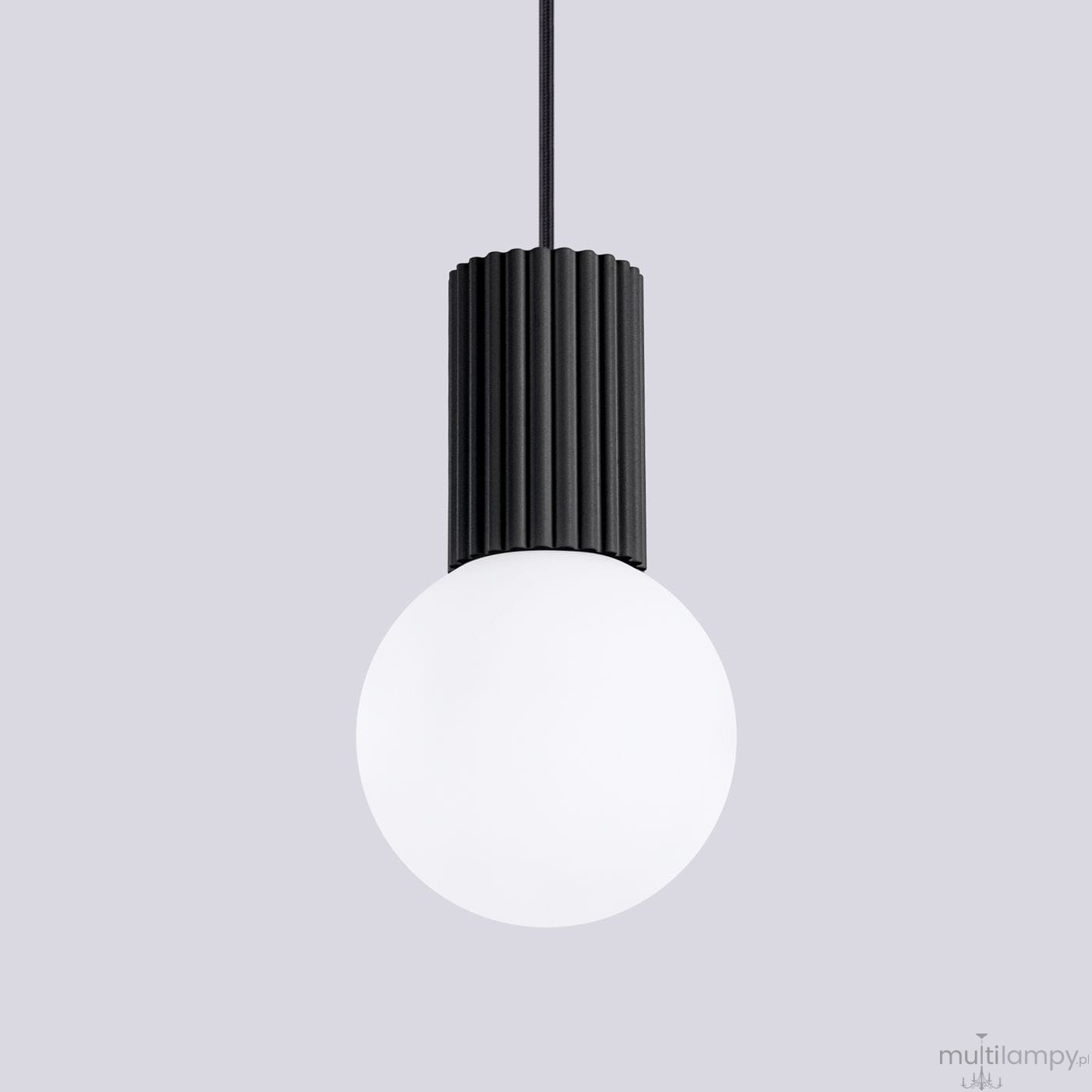 Lampa wisząca Halo 1xG9 w kolorze czarnym z cylindrycznym, żebrowanym kloszem i okrągłą, białą żarówką. Zawieszona na cienkim kablu w prostym, minimalistycznym stylu. Tło w jasnoszarym kolorze.