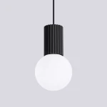 Lampa wisząca Halo 1xG9 w kolorze czarnym z cylindrycznym, żebrowanym kloszem i okrągłą, białą żarówką. Zawieszona na cienkim kablu w prostym, minimalistycznym stylu. Tło w jasnoszarym kolorze.