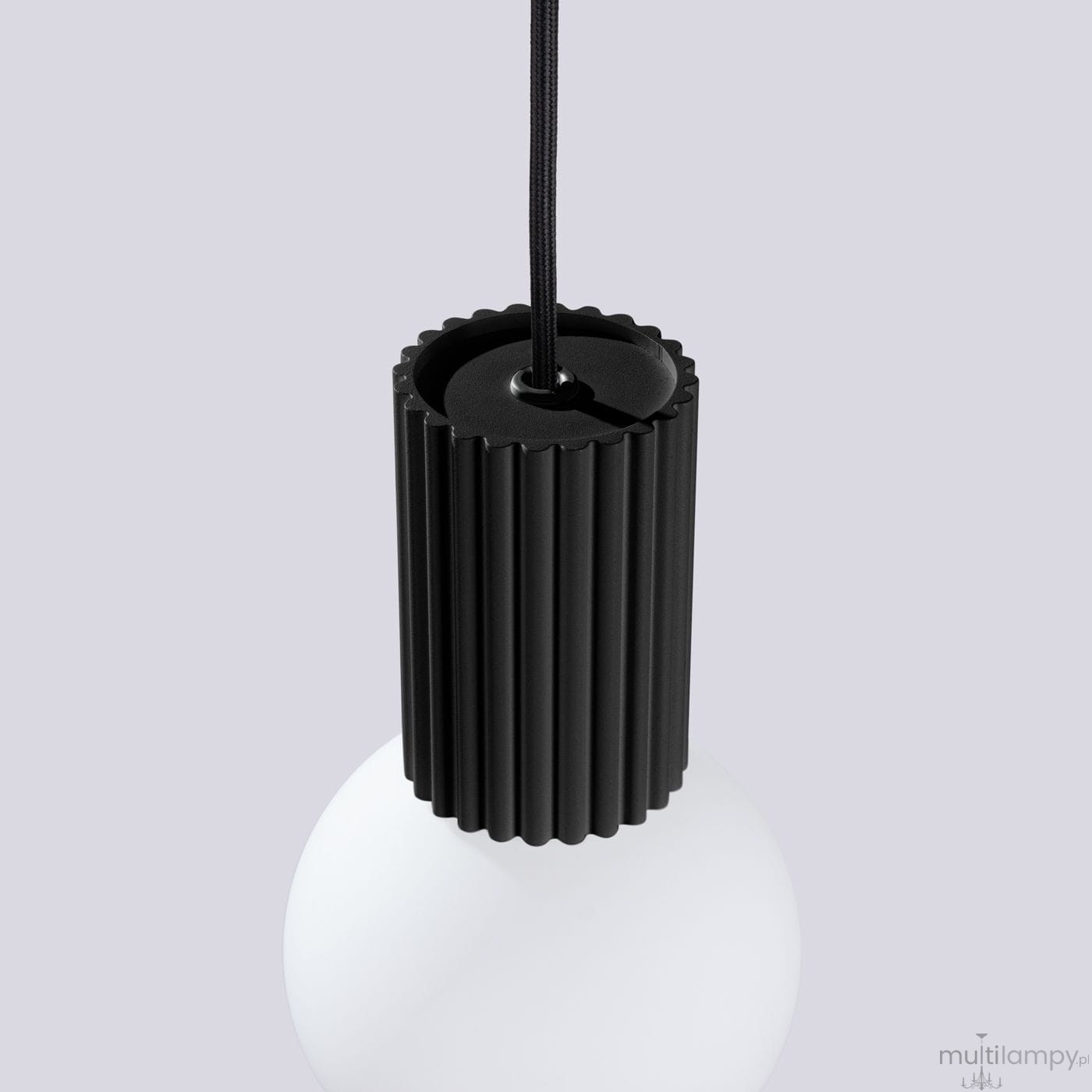 Czarna lampa wisząca Halo z oprawą w kształcie cylindrycznym z rowkami, zawieszona na czarnym przewodzie. Dolna część lampy to biała, okrągła kula. Ujęcie z góry, ukazujące detal mocowania.