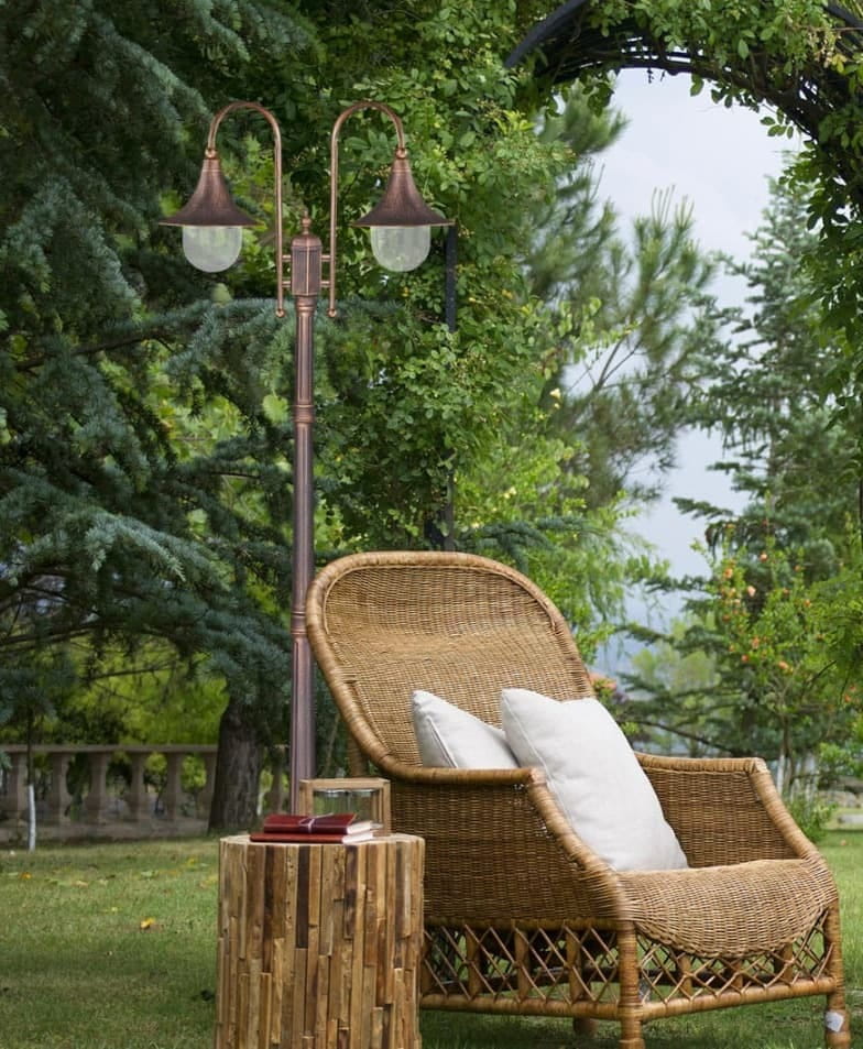 Lampa ogrodowa stojąca Boston H220 z dwoma kloszami E27, w kolorze czarnym i złotym. Ustawiona obok rattanowego fotela i stołu, z widocznym otoczeniem zieleni. Klosze mają kształt dzwonu, a lampa ma elegancki, klasyczny design.