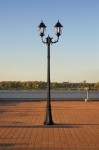 Lampa ogrodowa Lozana H243, stojąca, wykonana z czarnego metalu, z dwiema kloszami w stylu retro. Ujęcie frontalne, prezentujące lampę na tle nieba, z prostokątną podstawą i dekoracyjnym wzorem na słupie. Idealna do oświetlenia przestrzeni zewnętrznych.