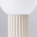 Beżowa lampa stołowa Halo z podstawą o żłobionej fakturze i okrągłym kloszem z białego szkła. Produkt widoczny z bliska, ukazujący detale podstawy oraz górną część z kloszem. Tło szare, neutralne.