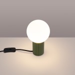 Lampa stołowa Halo w kolorze zielonej oliwki, z okrągłą, białą żarówką G9. Ustawiona na płaskiej powierzchni, z widocznym czarnym kablem i włącznikiem. Podstawa o fakturze żłobkowanej, tworzy minimalistyczny i nowoczesny design.
