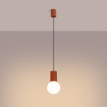 Lampa wisząca Halo z pojedynczym źródłem światła G9, w kolorze ochra czerwona. Produkt zawieszony na czarnym przewodzie, z cylindrycznym uchwytem o teksturowanej powierzchni. Kulista żarówka w dolnej części. Tło w stonowanej tonacji.
