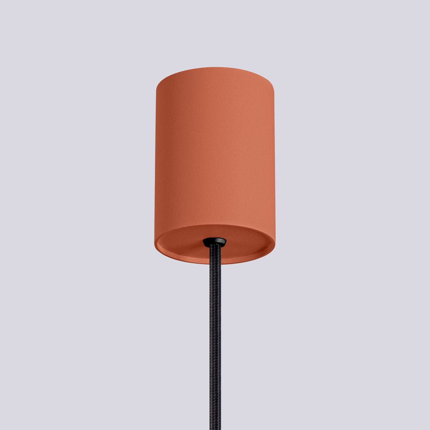 Lampa wisząca Halo o cylindrycznym kloszu w odcieniu ochry czerwonej, zawieszona na czarnym przewodzie. Klosz ma matową teksturę, a całość prezentuje się w frontalnym ujęciu na jednolitym tle.