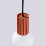 Lampa wisząca Halo z kloszem w kształcie kuli, z czerwonym, żłobionym uchwytem. Uchwyt łączy się z czarnym kablem. Tło w jasnym odcieniu szarości, podkreślające kolor i fakturę lampy. Idealna do nowoczesnych wnętrz.
