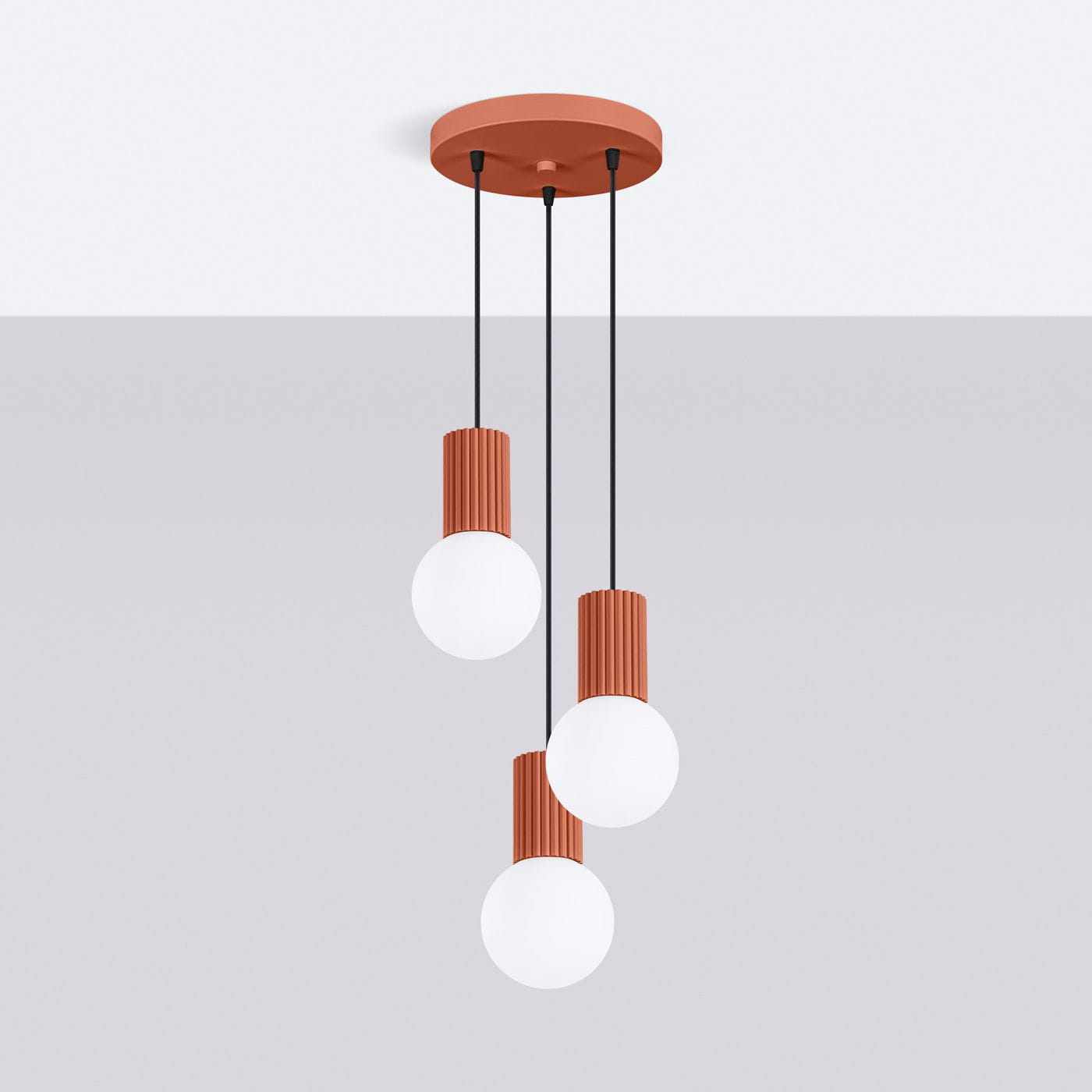 Lampa wisząca Halo 3xG9 w kolorze ochra czerwona. Składa się z trzech kulistych kloszy z mlecznego szkła na cylindrycznych, żebrowanych podstawach, zawieszonych na czarnych linkach z okrągłym mocowaniem sufitowym.