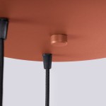 Lampa wisząca Halo w kolorze ochra czerwona z trzema miejscami na żarówki G9. Widać gładką, matową powierzchnię klosza oraz dwa czarne przewody zawieszenia. Klosz ma okrągły kształt i jest zamocowany do sufitu.