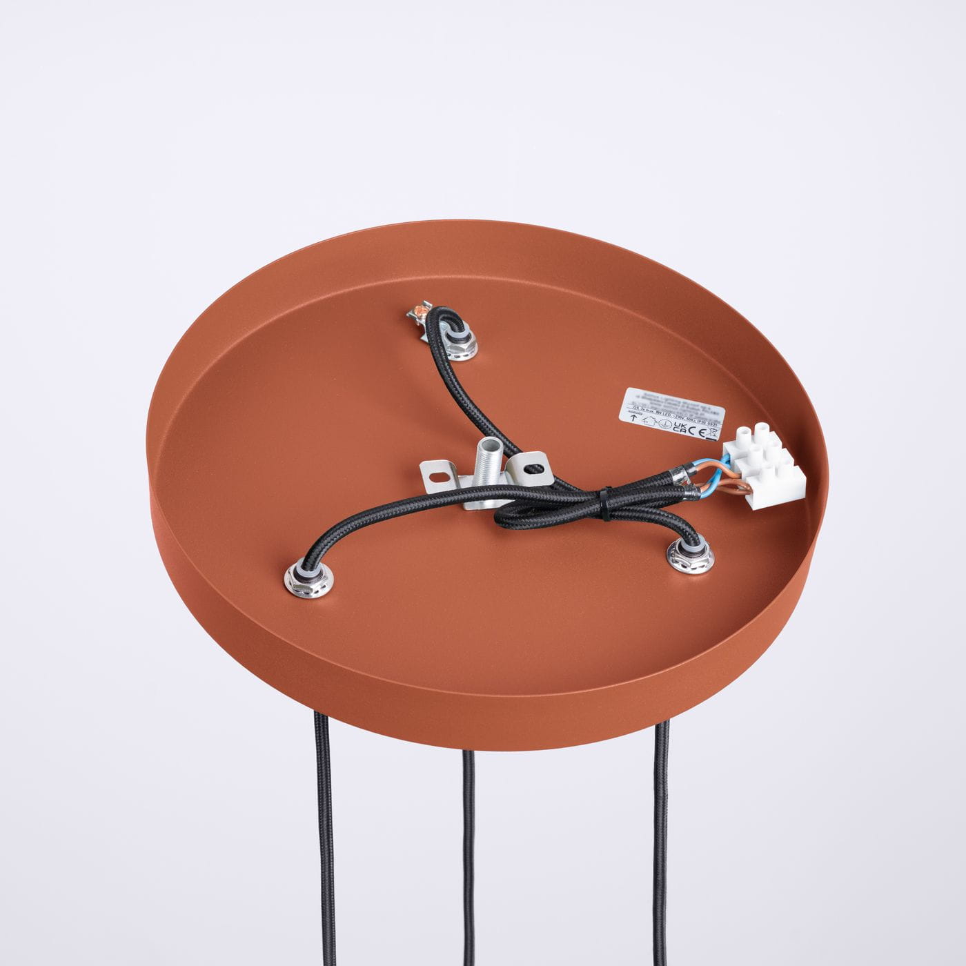 Lampa wisząca Halo w kolorze ochra czerwona, z okrągłym, matowym uchwytem. Widoczne trzy przewody z końcówkami oraz miejsce na trzy żarówki G9. Tło białe, produkt widoczny z góry.