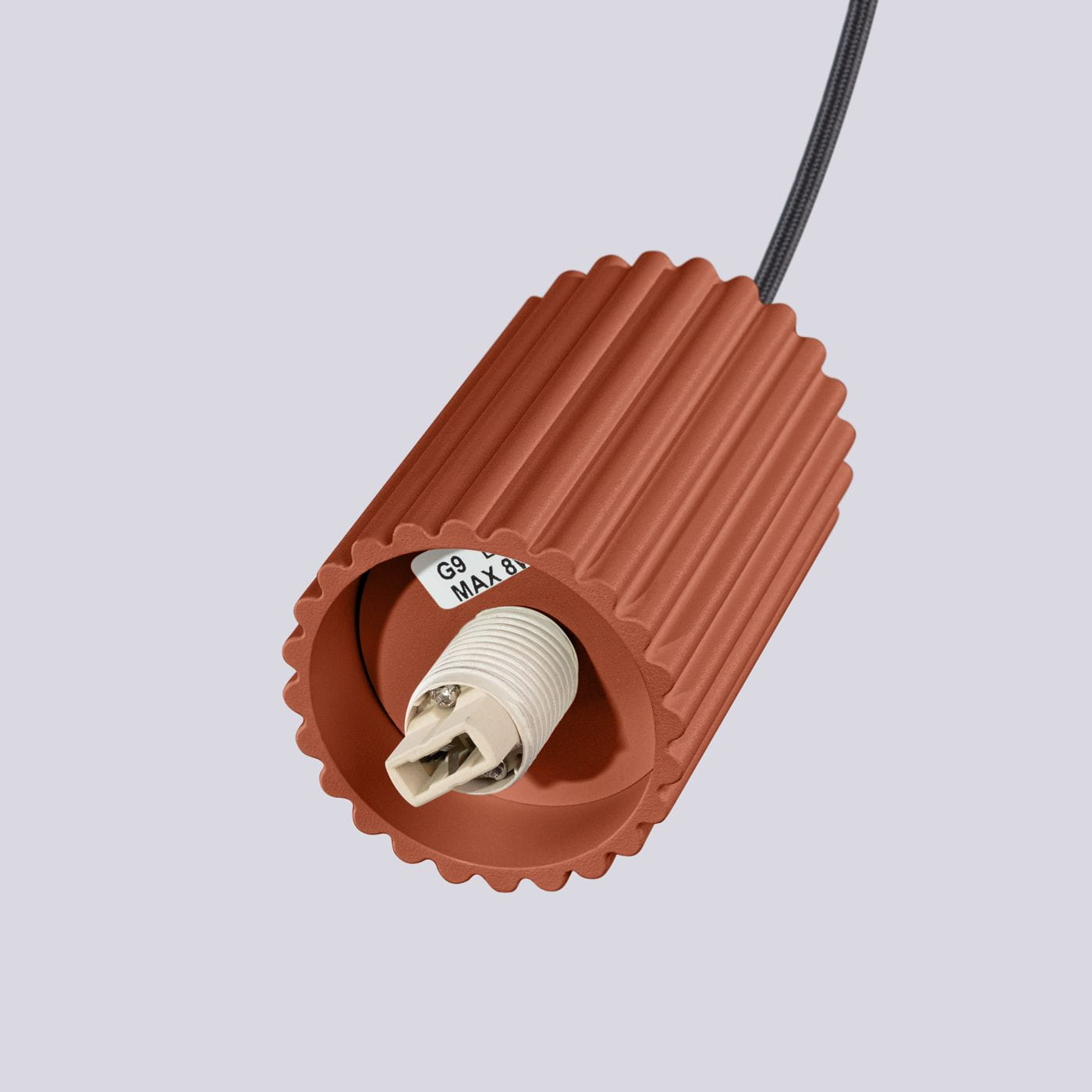 Lampa wisząca Halo w kolorze ochra czerwona, z gładką, teksturowaną obudową w kształcie cylindra. Widoczny gwint G9 do żarówki oraz czarny kabel zawieszenia. Ujęcie z góry, pokazujące detal mocowania.
