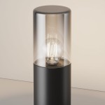 Lampa ogrodowa Amas H25 w kolorze grafitowym, stojąca, z kloszem z przezroczystego szkła, widoczna żarówka E27 w środku. Produkt ukazany w zbliżeniu, na jednolitym tle.