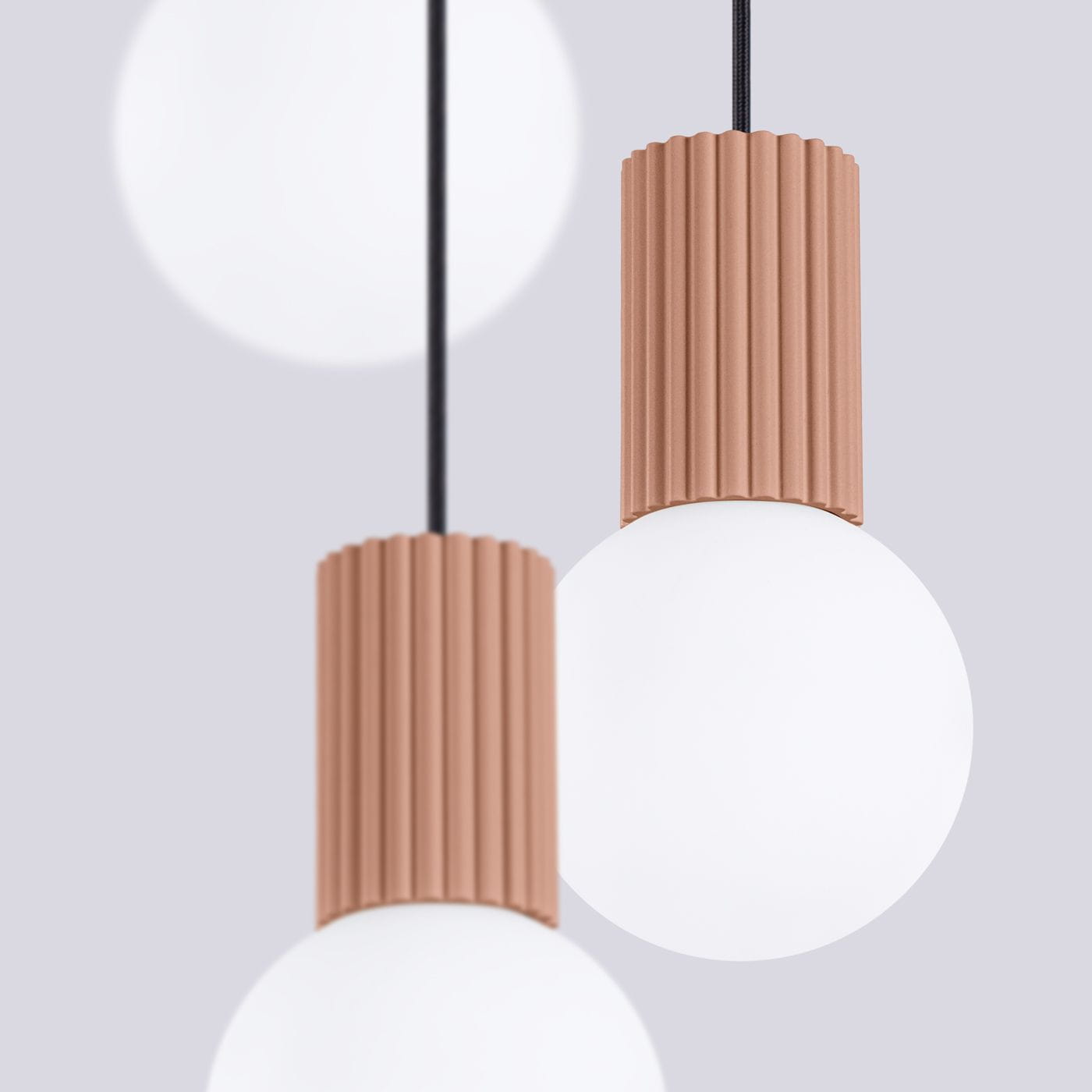 Lampa wisząca Halo mocca SL.1735 z trzema oprawami G9, z cylindrycznymi, falistymi osłonami w kolorze terakoty oraz białymi, szklanymi kulami. Produkt zawieszony na czarnym przewodzie, na jednolitym szarym tle.