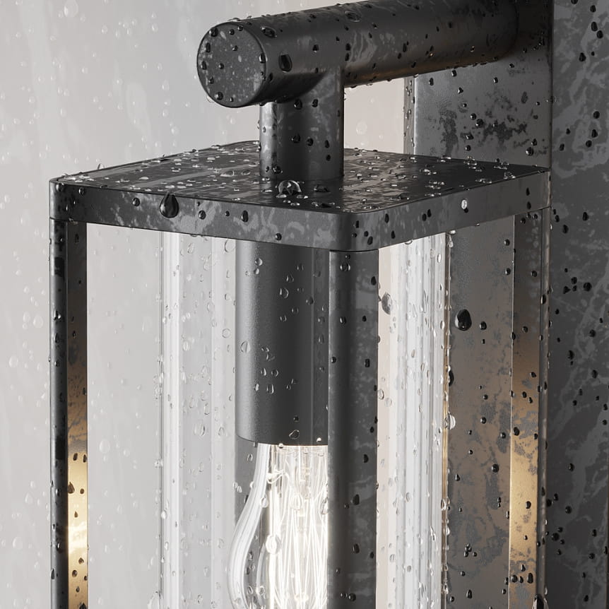 Kinkiet elewacyjny Cell w kolorze grafitowym, z metalową obudową i przezroczystym szkłem, z widoczną żarówką E27. Zdjęcie ukazuje detale lampy, z kroplami wody na powierzchni, co podkreśla jej odporność na warunki atmosferyczne.