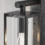 Kinkiet elewacyjny Cell w kolorze grafitowym, z metalową obudową i przezroczystym szkłem, z widoczną żarówką E27. Zdjęcie ukazuje detale lampy, z kroplami wody na powierzchni, co podkreśla jej odporność na warunki atmosferyczne.