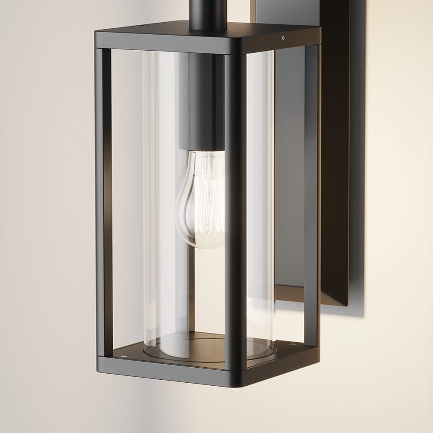Kinkiet elewacyjny Cell w kolorze grafitowym, z przezroczystym kloszem i widoczną żarówką E27. Ujęcie z boku, ukazujące prostokątną formę oraz metalową konstrukcję. Idealny do oświetlenia zewnętrznego.