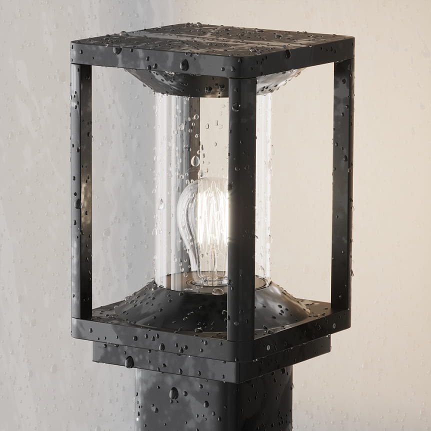 Lampa ogrodowa Cell H75 w kolorze grafitowym, stojąca, z kloszem ze szkła i metalową podstawą. Widoczna żarówka E27. Produkt w detalu, z kroplami wody na powierzchni, co sugeruje odporność na warunki atmosferyczne.
