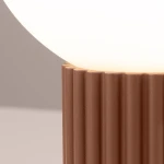 Lampa stołowa Halo z podstawą w kolorze mocca, o teksturowanej, żłobkowanej fakturze. Górna część to okrągła, mlecznobiała kula. Ujęcie z boku, ukazujące detale podstawy.