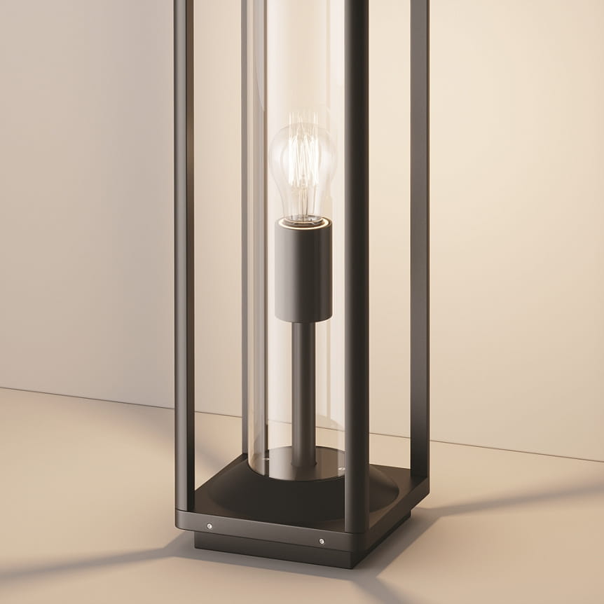 Grafitowa lampa ogrodowa Cell H50 stojąca z oprawą na żarówkę E27. Posiada szklany klosz, metalową podstawę oraz widoczną żarówkę w środku. Ujęcie z boku, na jednolitym tle.