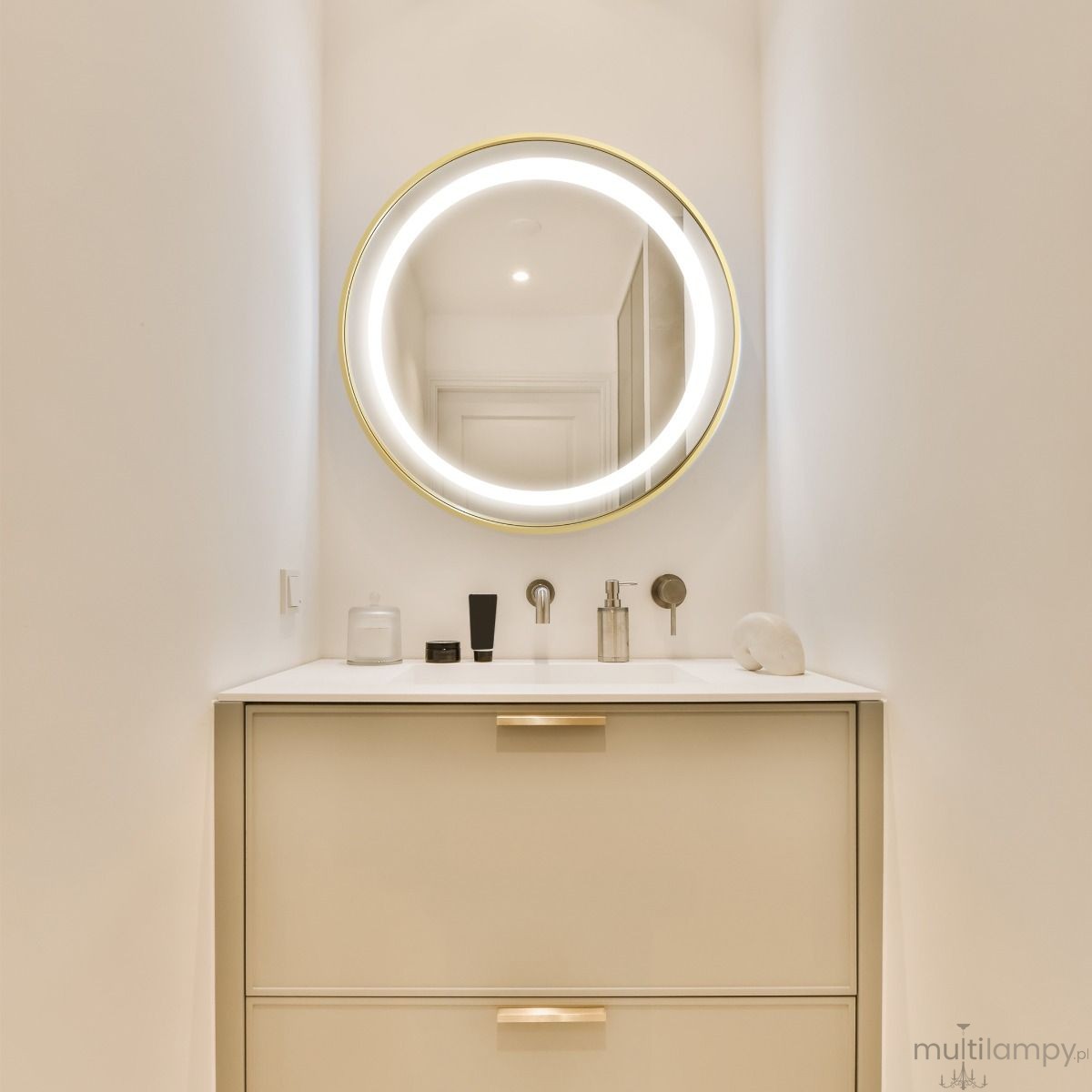 Lustro podświetlane D60 w kształcie koła, z błyszczącą złotą ramą i oświetleniem LED. Zawieszone nad minimalistyczną umywalką z szufladami. Tło jasne, w nowoczesnej łazience. Widoczne akcesoria na blacie, w tym kosmetyki i pojemniki.