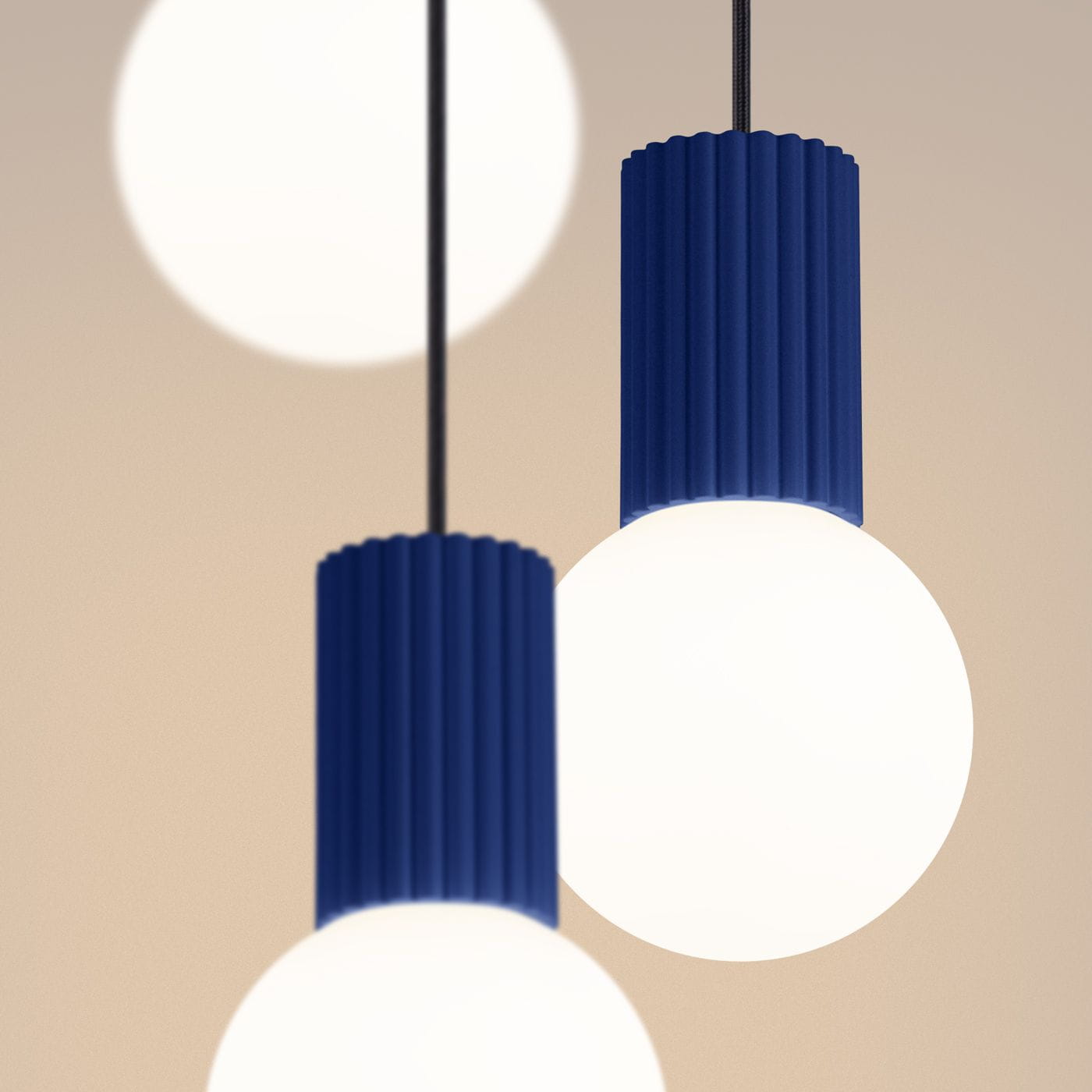 Lampa wisząca Halo 3xG9 w kolorze niebieskim z cylindrycznymi, żłobionymi osłonami oraz okrągłymi, białymi kloszami. Ujęcie zbliżeniowe na detale lampy, w tle rozmyte źródła światła.