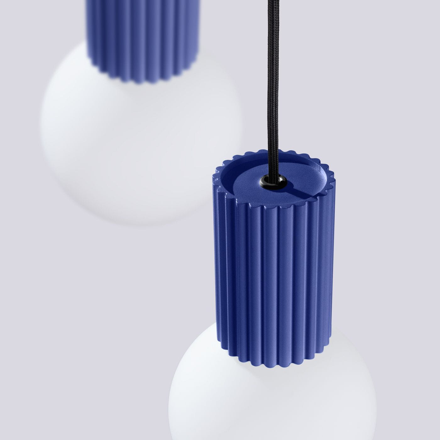 Lampa wisząca Halo 3xG9 w kolorze niebieskim z okrągłym, matowym kloszem. U góry widoczny jest niebieski, teksturowany uchwyt z rowkami, z czarnym przewodem zawieszającym. Kąt ujęcia zbliżeniowy, na jednolitym tle.