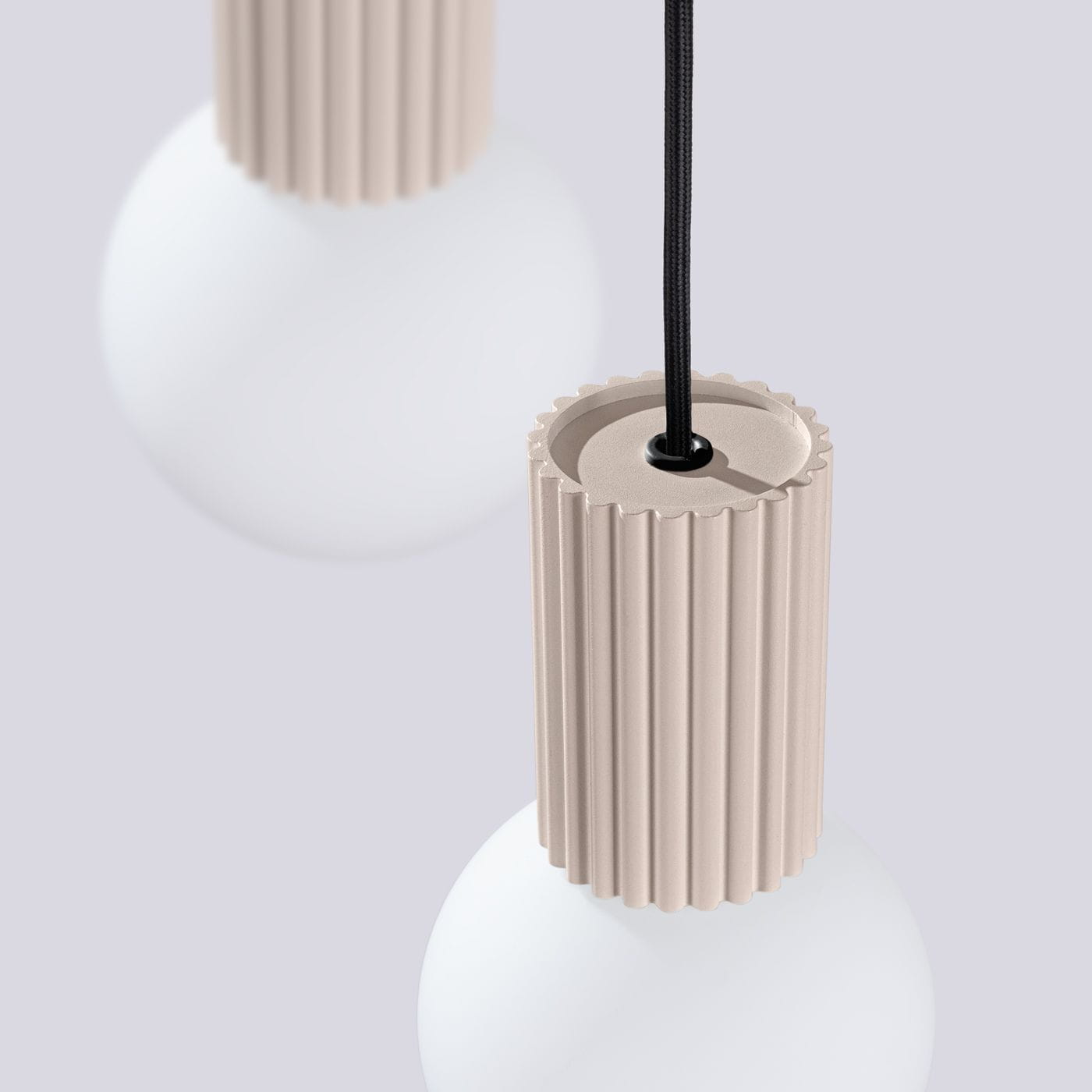 Lampa wisząca Halo w kolorze taupe z trzema oprawami G9. Widoczny detal cylindrycznego uchwytu z rowkami oraz biała, okrągła kula. Produkt zawieszony na czarnym przewodzie, na jednolitym tle.