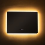 Lustro podświetlane 70x50 cm, prostokątne, bezramkowe, z podświetleniem LED 24W CCT. Ujęcie frontalne, włączniki dotykowe w dolnej części. Otoczenie w ciepłym, stonowanym odcieniu ściany.