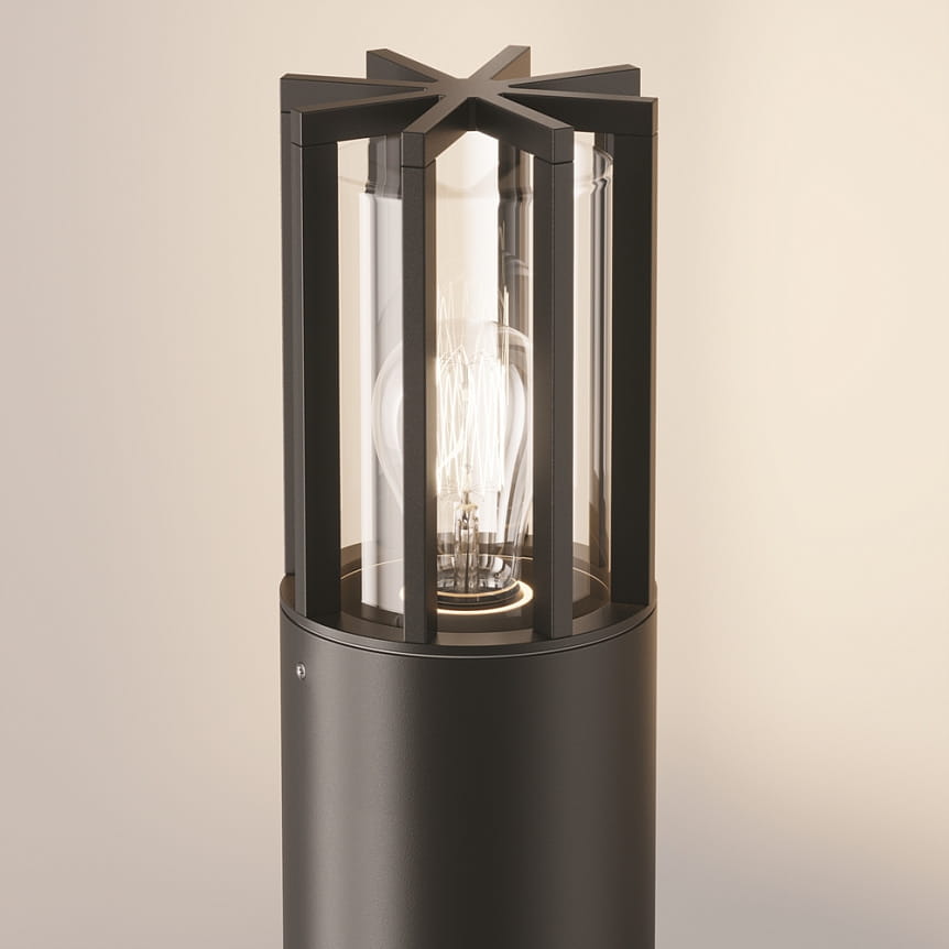 Lampa ogrodowa Barrel H75, stojąca, w kolorze grafitowym. Okrągła podstawka z matowego metalu, osłona z przezroczystego szkła z dekoracyjnymi żeberkami. Widoczna żarówka E27 wewnątrz. Ujęcie z góry, podkreślające detale konstrukcji.