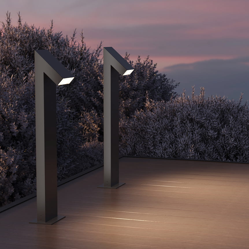 Grafitowa lampa ogrodowa LED Guss H90 o mocy 15W i temperaturze barwowej 3000K, z charakterystycznym, prostokątnym kloszem, stojąca na stabilnej podstawie. Ujęcie z przodu, w tle krzewy i zmierzchowe niebo.