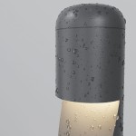 Grafitowa lampa ogrodowa LED Hagen H60 o mocy 5W i temperaturze barwowej 3000K, z widocznymi kroplami wody na powierzchni, w kształcie cylindrycznym. Emituje ciepłe światło z dolnej części, ustawiona prosto.