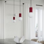 Lampa wisząca Halo 1xG9 w kolorze burgundowym z białymi kloszami w kształcie kul, zawieszona na czarnych przewodach. W tle widoczne zasłony i okno z widokiem na miasto. Na stole ceramiczna dekoracja w białym kolorze.