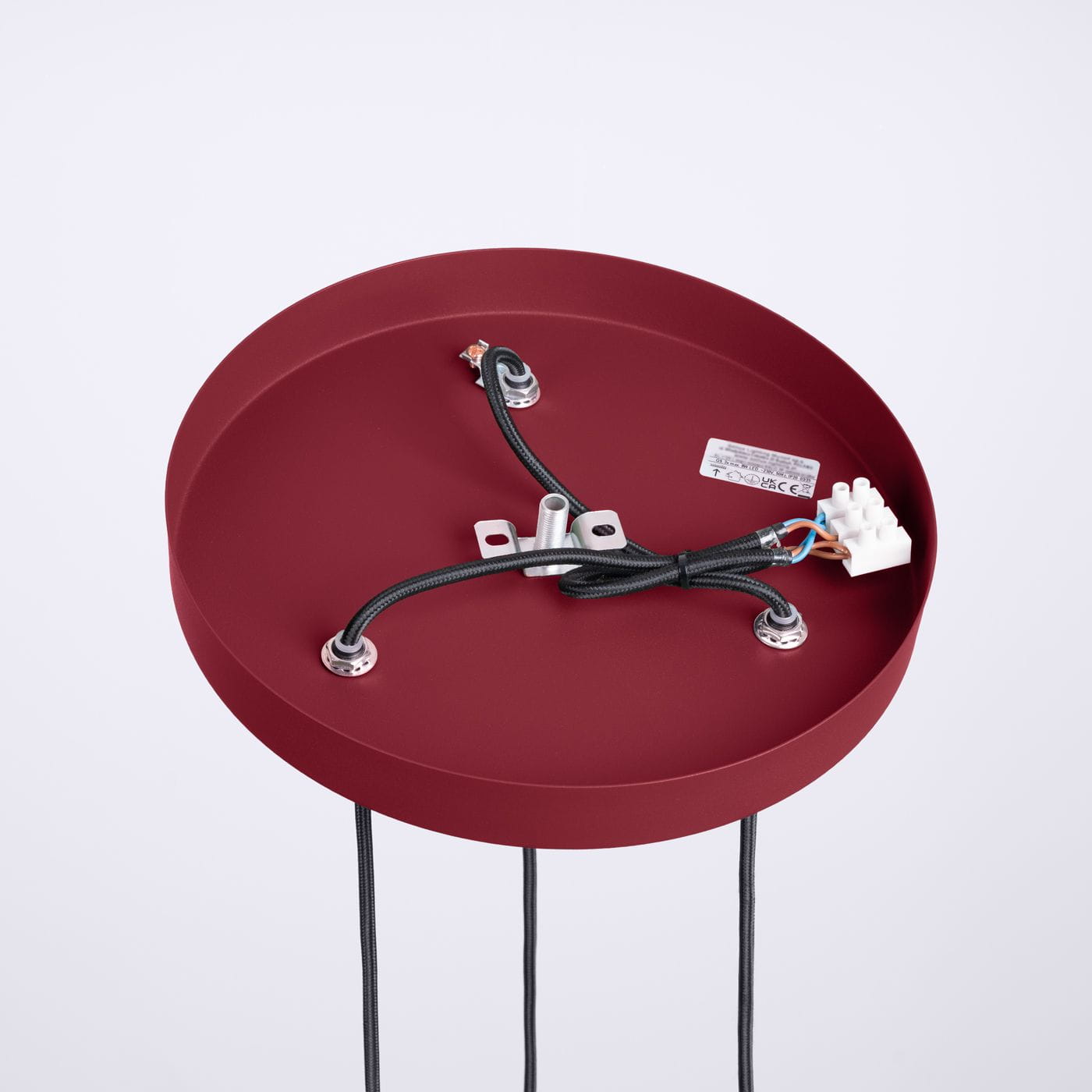 Burgundowa lampa wisząca Halo z trzema gniazdami G9. Widok od góry, okrągła podstawa z matowej powierzchni, widoczne przewody elektryczne oraz elementy montażowe. Proste tło podkreśla kolor i kształt lampy.