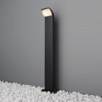 Lampa ogrodowa LED Stock H80 w kolorze grafitowym, o wysokości 80 cm, z ujęciem frontalnym. Wyposażona w źródło światła 7W, emituje ciepłe światło 3000K. Prosta, smukła konstrukcja z lekko zaokrąglonym kloszem, umieszczona na białych kamieniach.