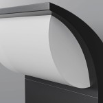 Kinkiet elewacyjny LED 7W w kolorze grafitowym, z białym kloszem o zaokrąglonym kształcie. Ujęcie z boku, eksponujące teksturę materiału oraz szczegóły konstrukcji. Elementy montażowe widoczne u podstawy.