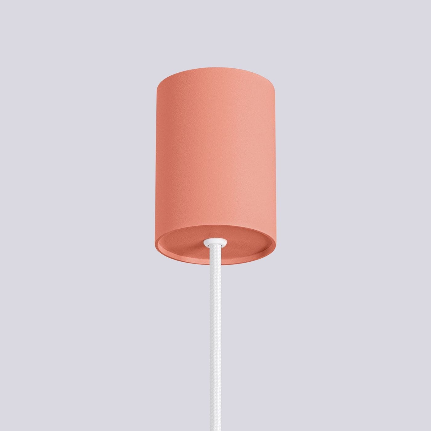 Lampa wisząca Halo w kolorze brzoskwiniowym z cylindrycznym kloszem, zawieszona na białym, plecionym przewodzie. Ujęcie z dołu, pokazujące detale klosza i sposób mocowania.