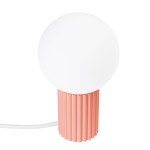 Lampa stołowa Halo w brzoskwiniowym kolorze z podstawą o teksturowanej, żebrowanej fakturze oraz okrągłym, białym kloszem. Ujęcie frontalne, widoczny kabel zasilający. Idealna do nowoczesnych wnętrz.