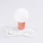 Lampa stołowa Halo 1xG9 w kolorze brzoskwiniowym z okrągłą, białą głowicą. Podstawa z delikatnym, teksturowanym wykończeniem. Widoczny biały kabel z włącznikiem. Ujęcie frontalne na białym tle.